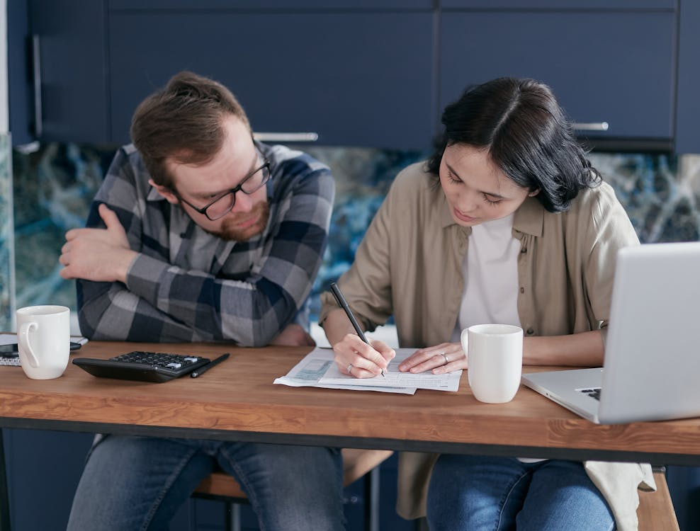 Couple reviewing documents and paperwork at home for the process of changing last name after marriage