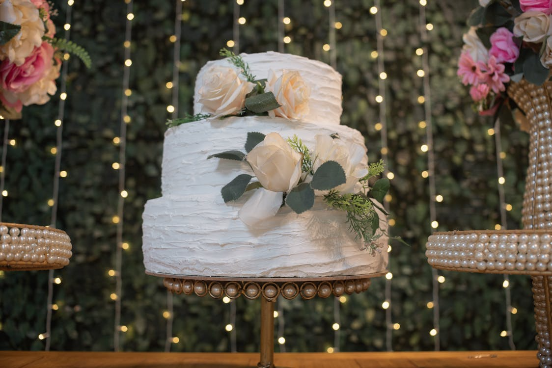 Wedding cake under warm string lights at a romantic spring evening reception