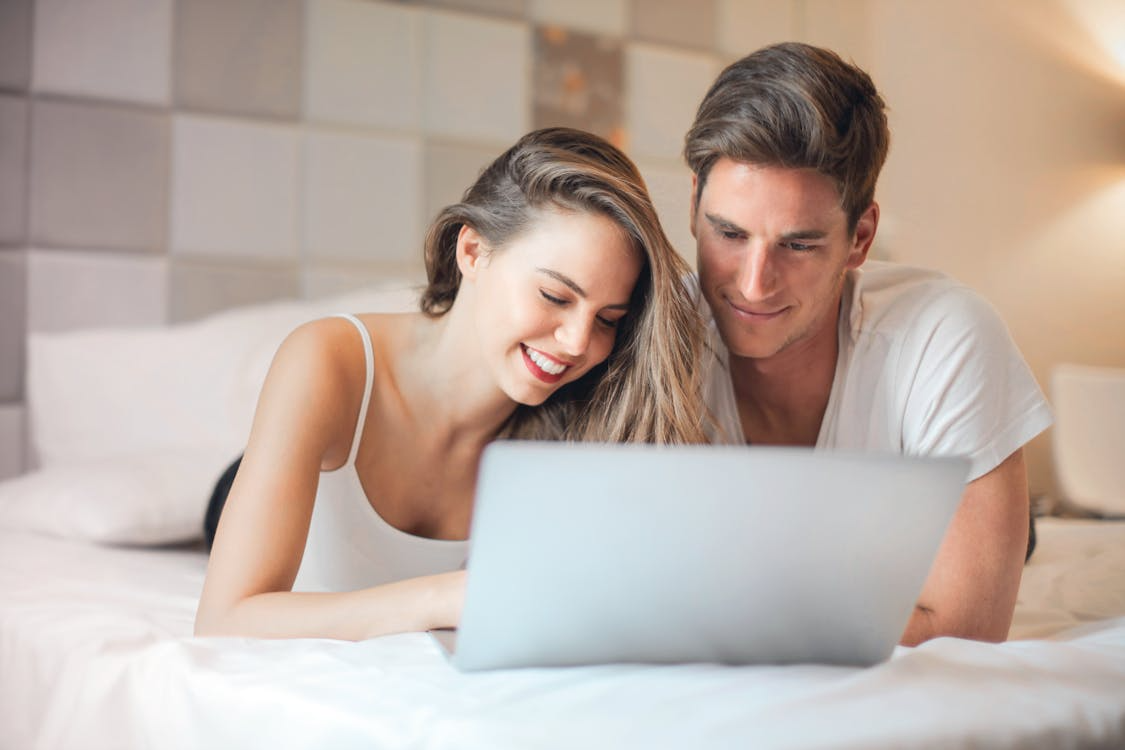 Smiling couple using a laptop together while planning their name change cost and next steps. 