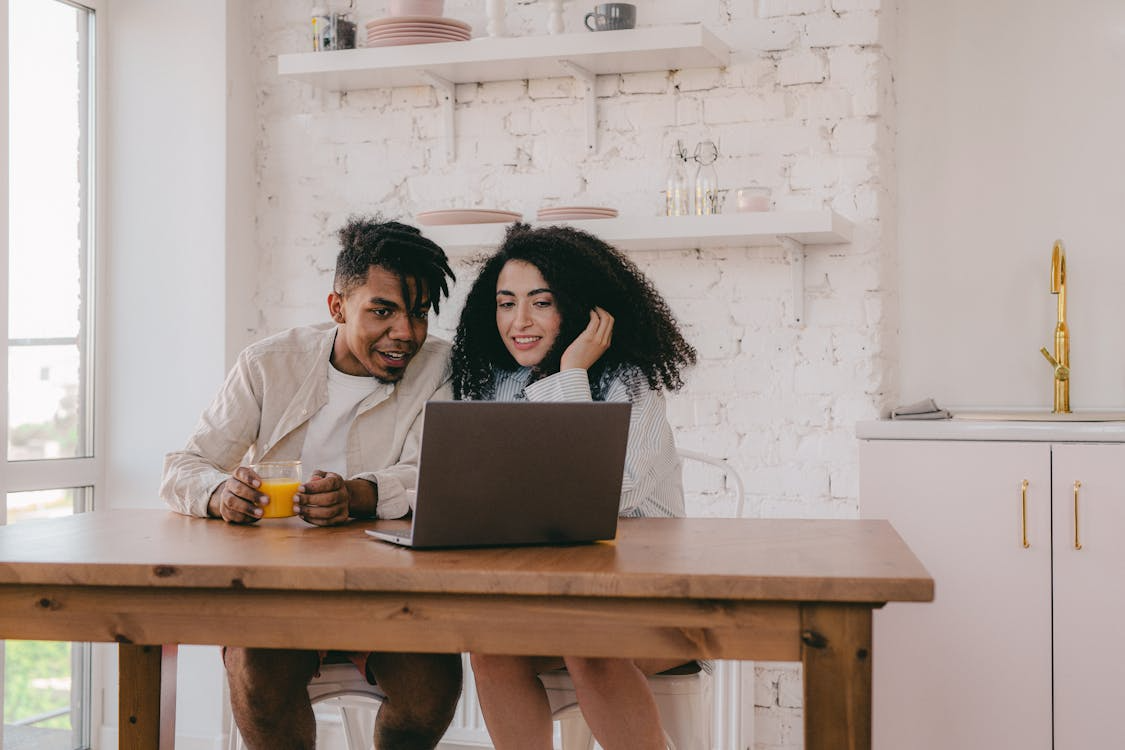 Couple sitting at home using a laptop together while starting their citizenship through marriage process.