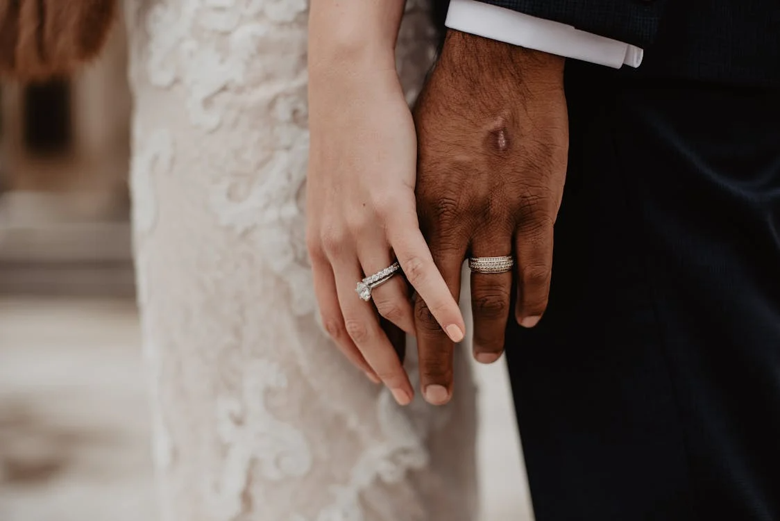 Close-up of wedding rings on couple’s hands, showing left-hand ring placement when you get married.