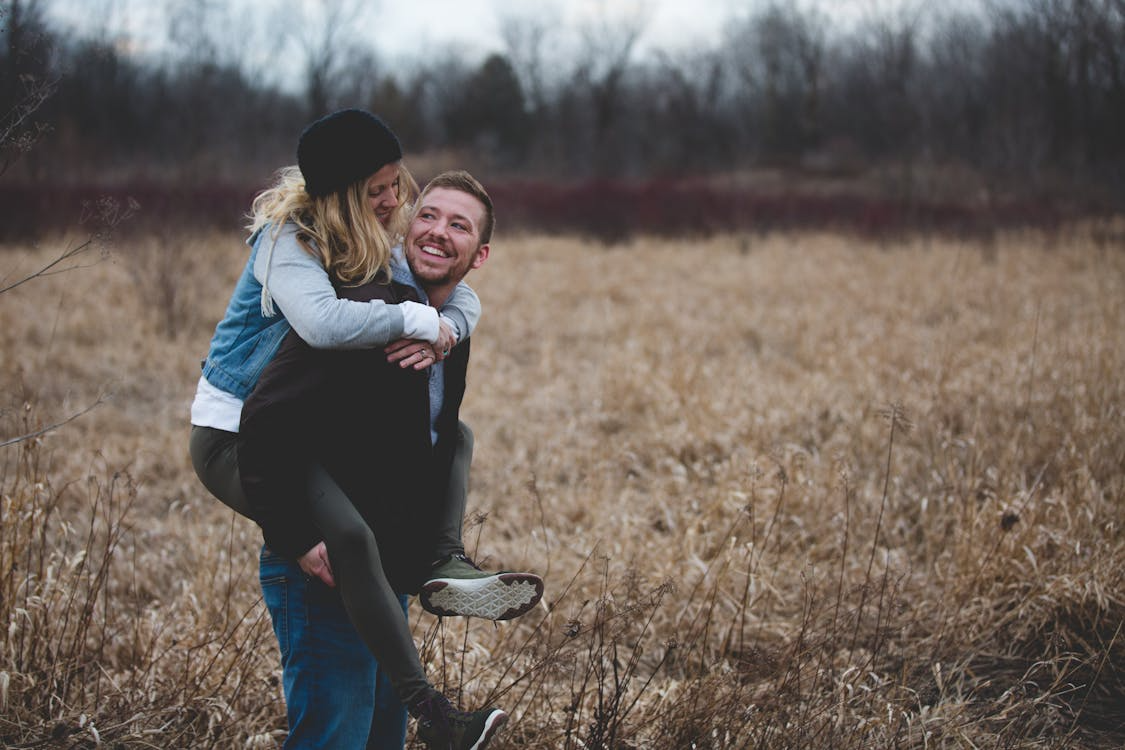 Couple in a field sharing a playful moment, illustrating what changes when you get married.