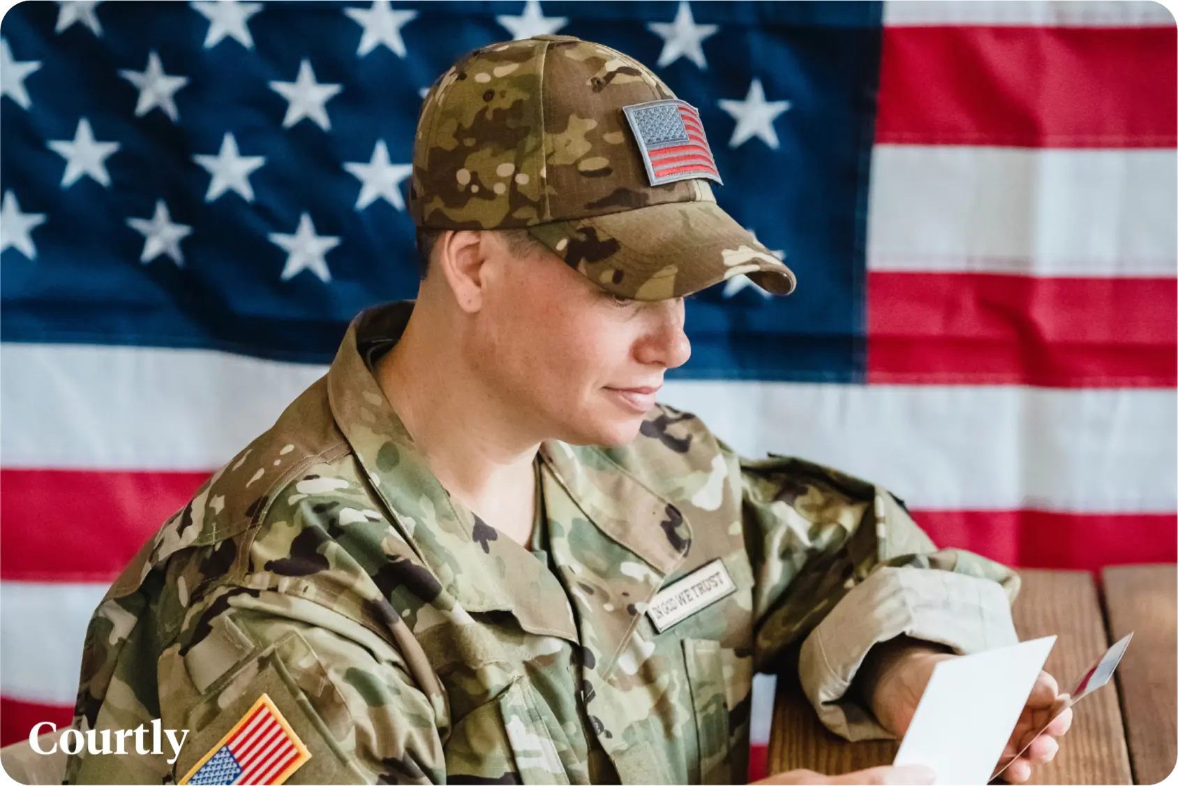 Military spouse benefits during deployment, U.S. service member reading a letter in uniform in front of a flag.