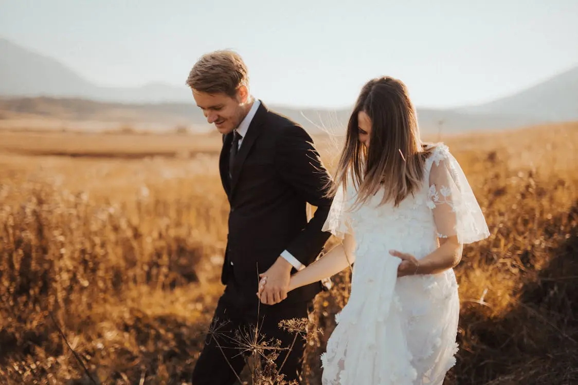 Newly married couple walking through a field, symbolizing what changes when you get married .