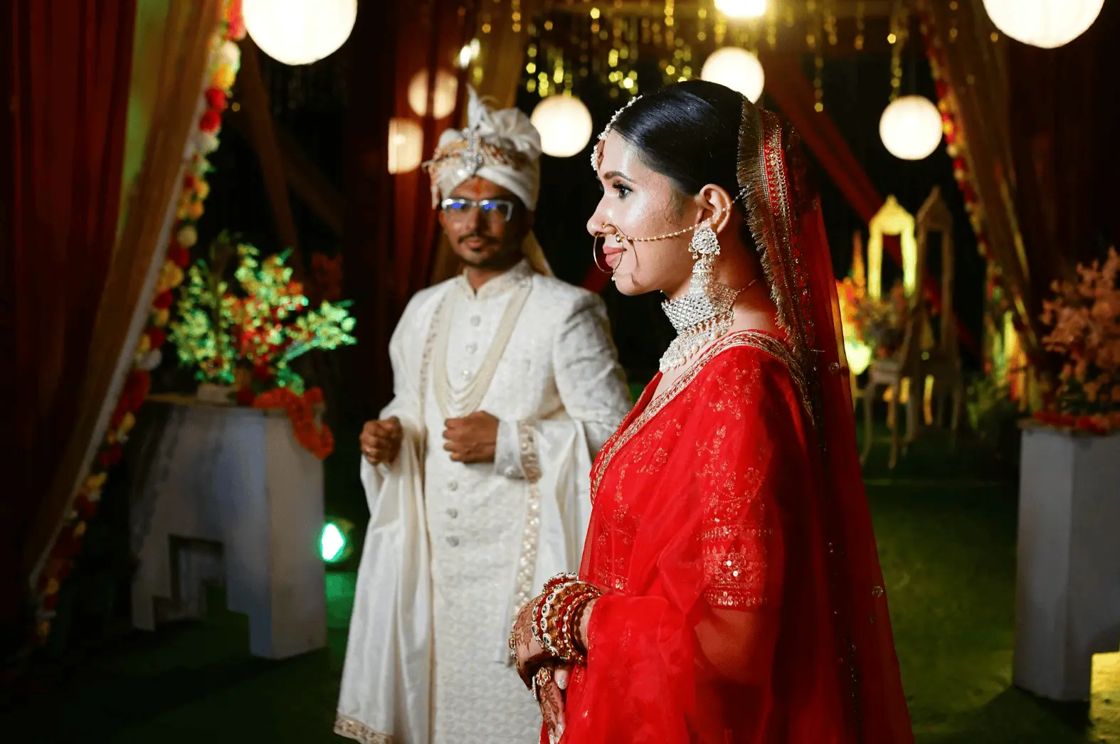Woman wearing a red and gold dress holding up henna decorated hands: wedding night traditions.