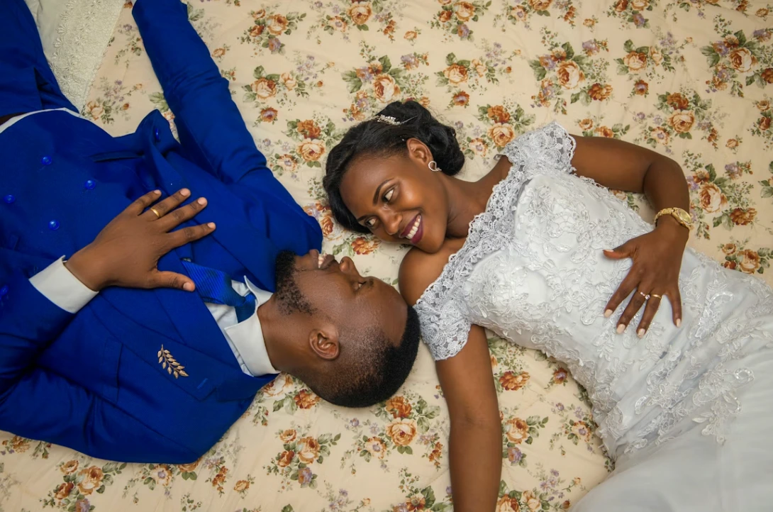 Groom in blue suit and bride in white gown smiling and laughing together at their wedding. American wedding traditions.