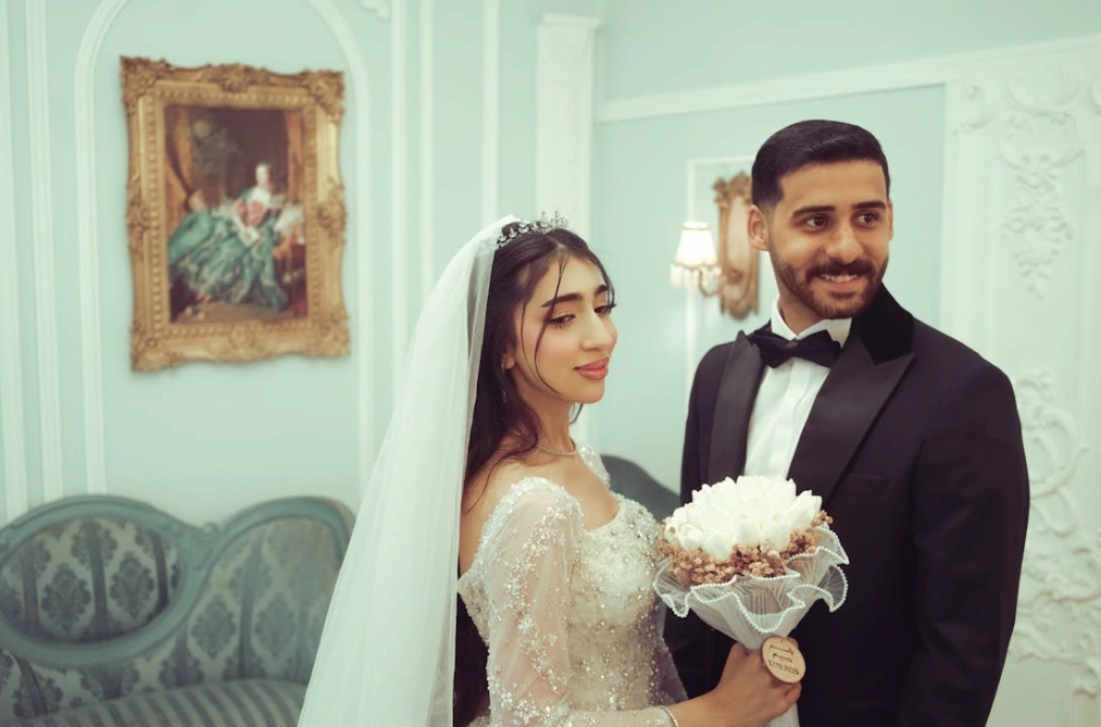 Modern indoor muslim wedding featuring bride in white gown and groom in black tux: Islamic marriage.