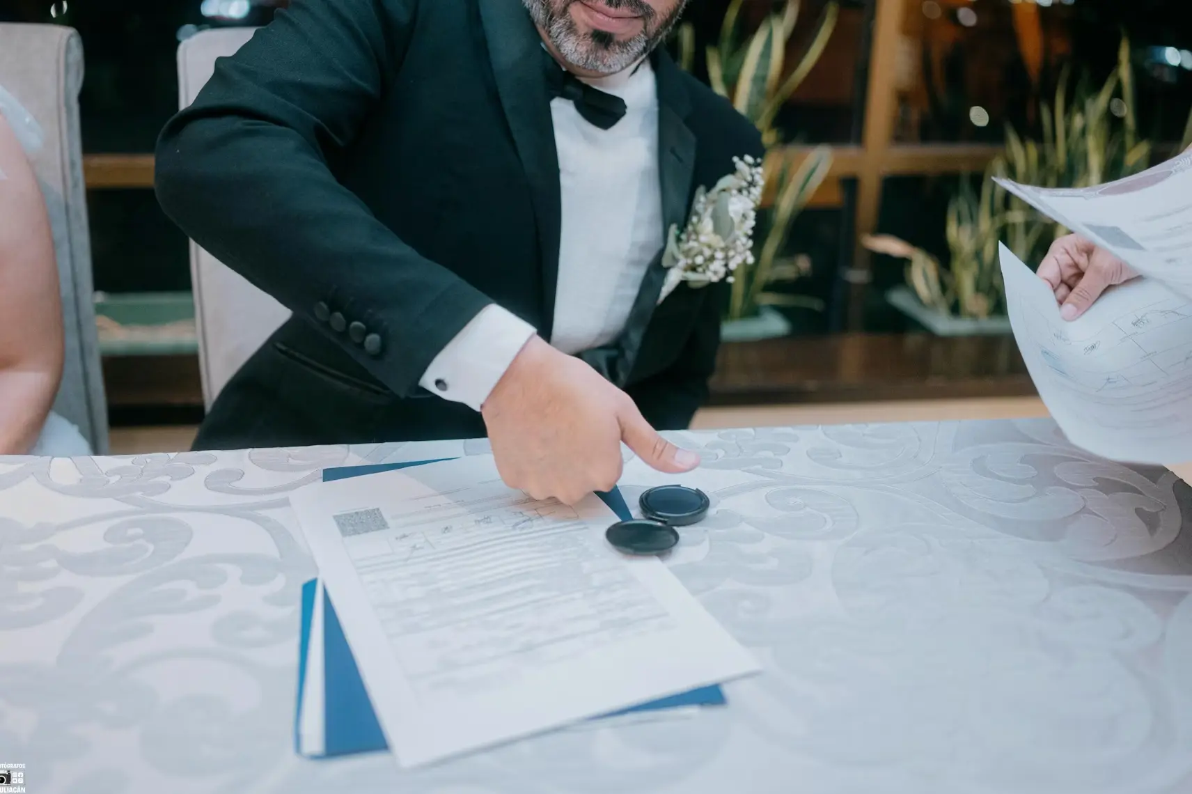 Groom giving his thumbprint as he signs paper: legal benefits of marriage.