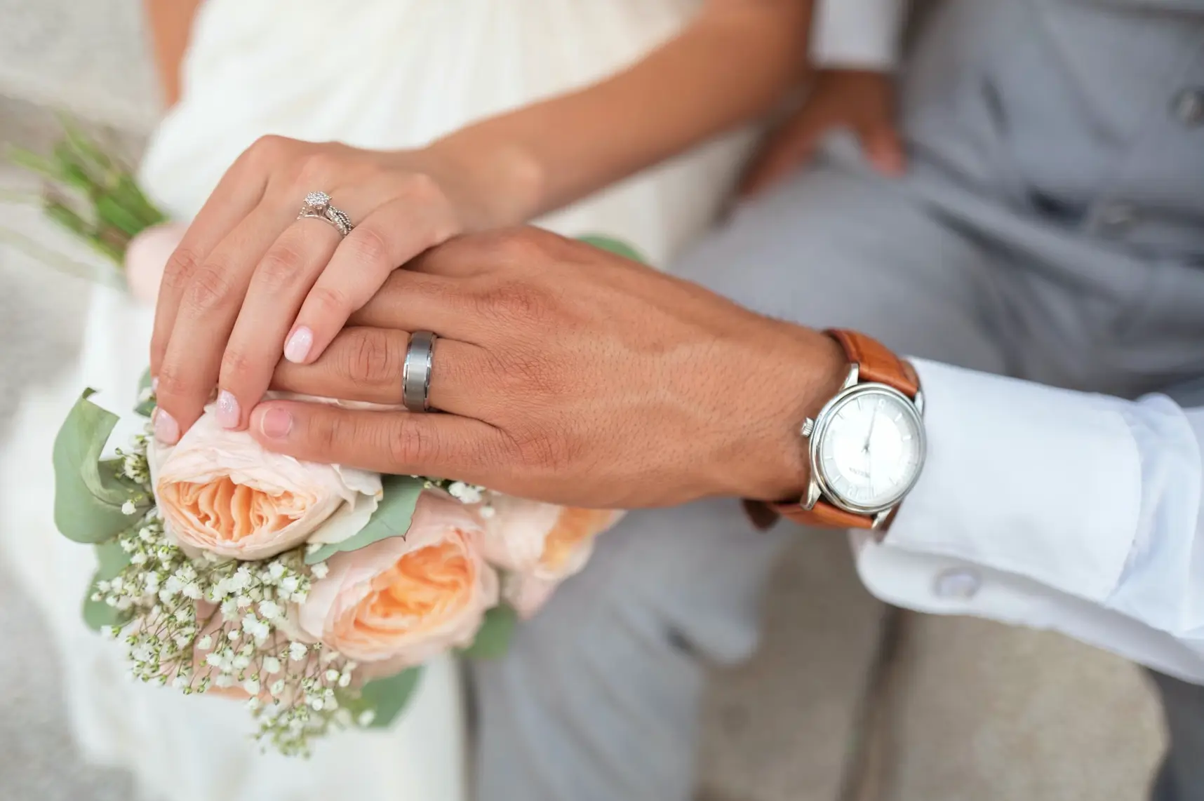 Bride and groom holding hands showcasing their wedding rings: legal age for marriage.