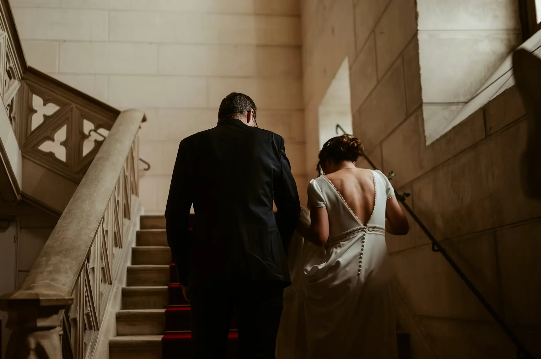 Bride and groom walking up stairs in courthouse to be married: civil marriage vs religious marriage.