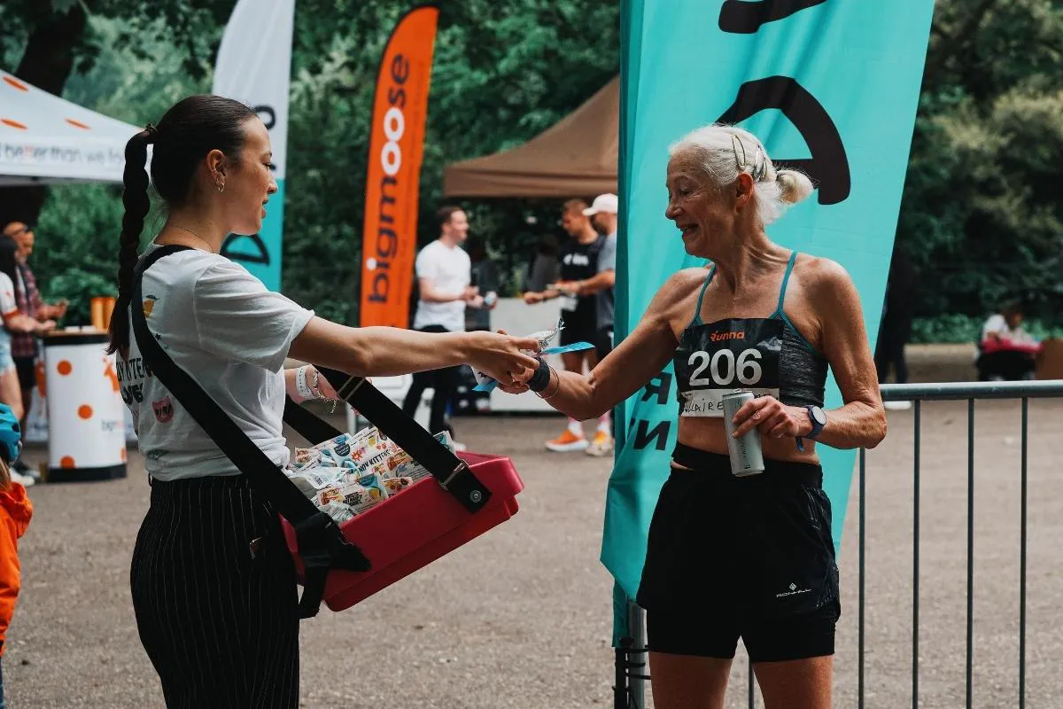Une femme donne de l'eau à un coureur.
