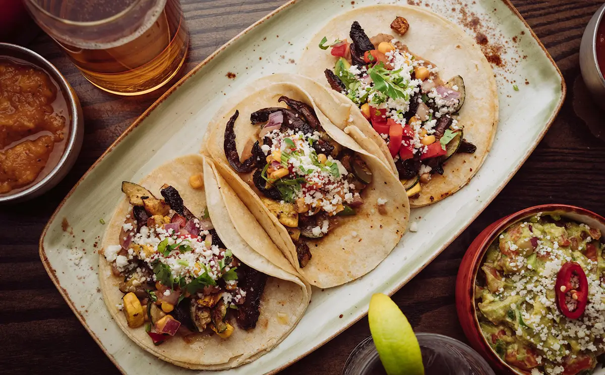 Trois tacos avec tomates, maïs, légumes et salsa.