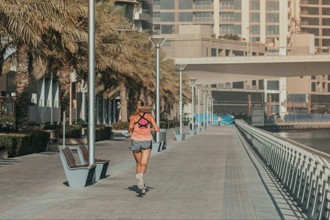 A woman running in a marina lined with palm trees