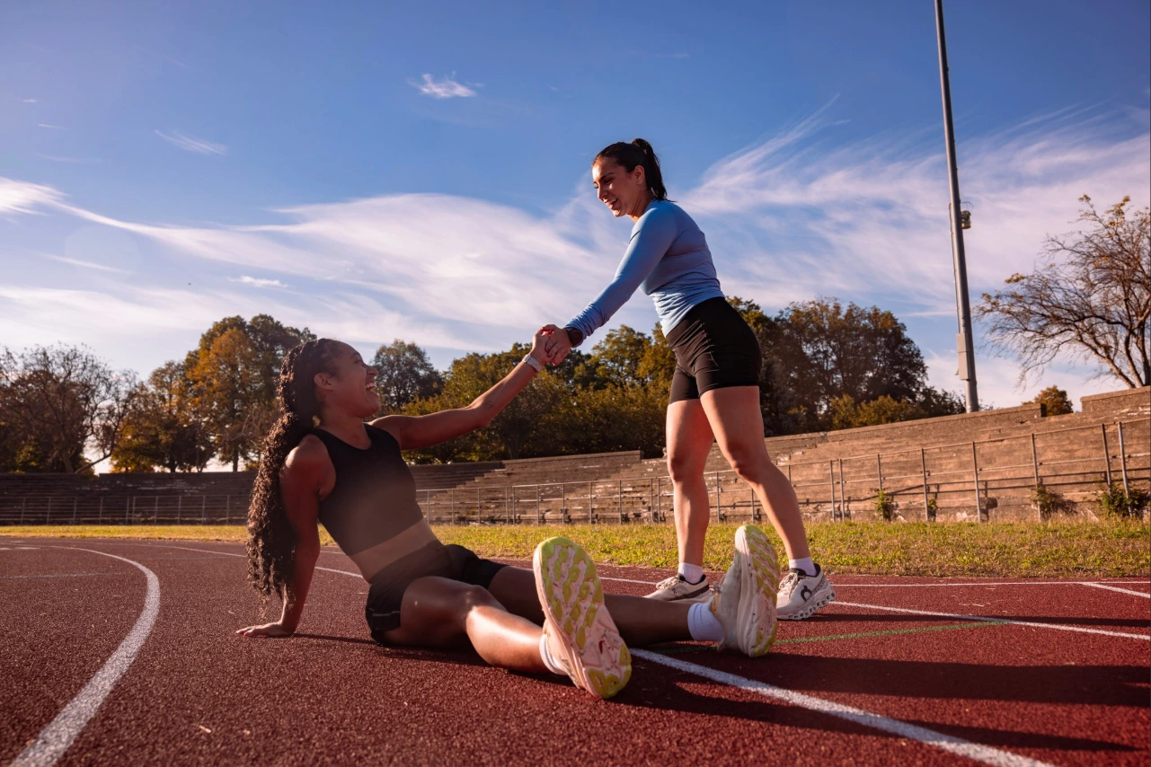 Runner helping a fellow friend up from the ground. 