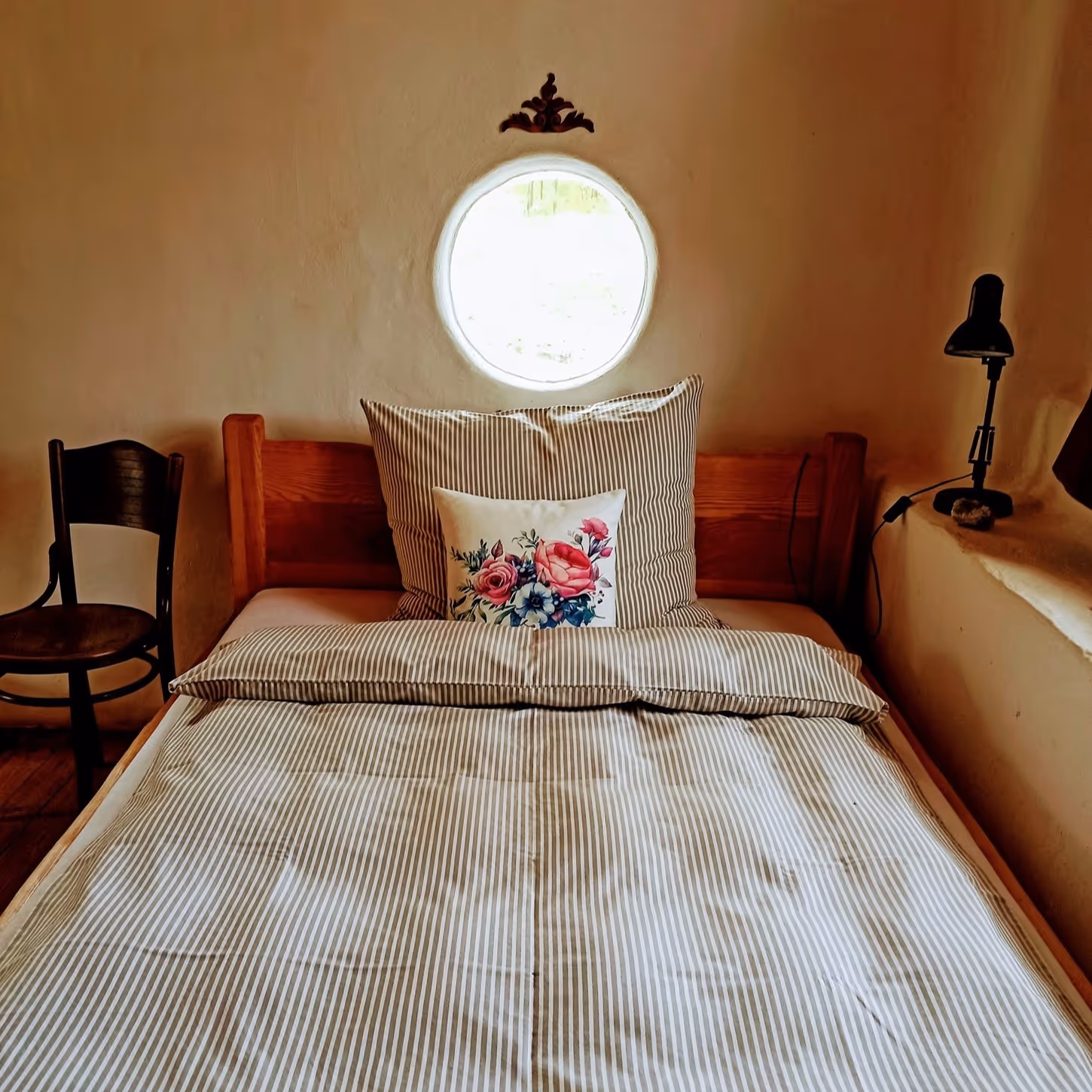 postel v tradičním povlečení s kulatým oknem na pelestí