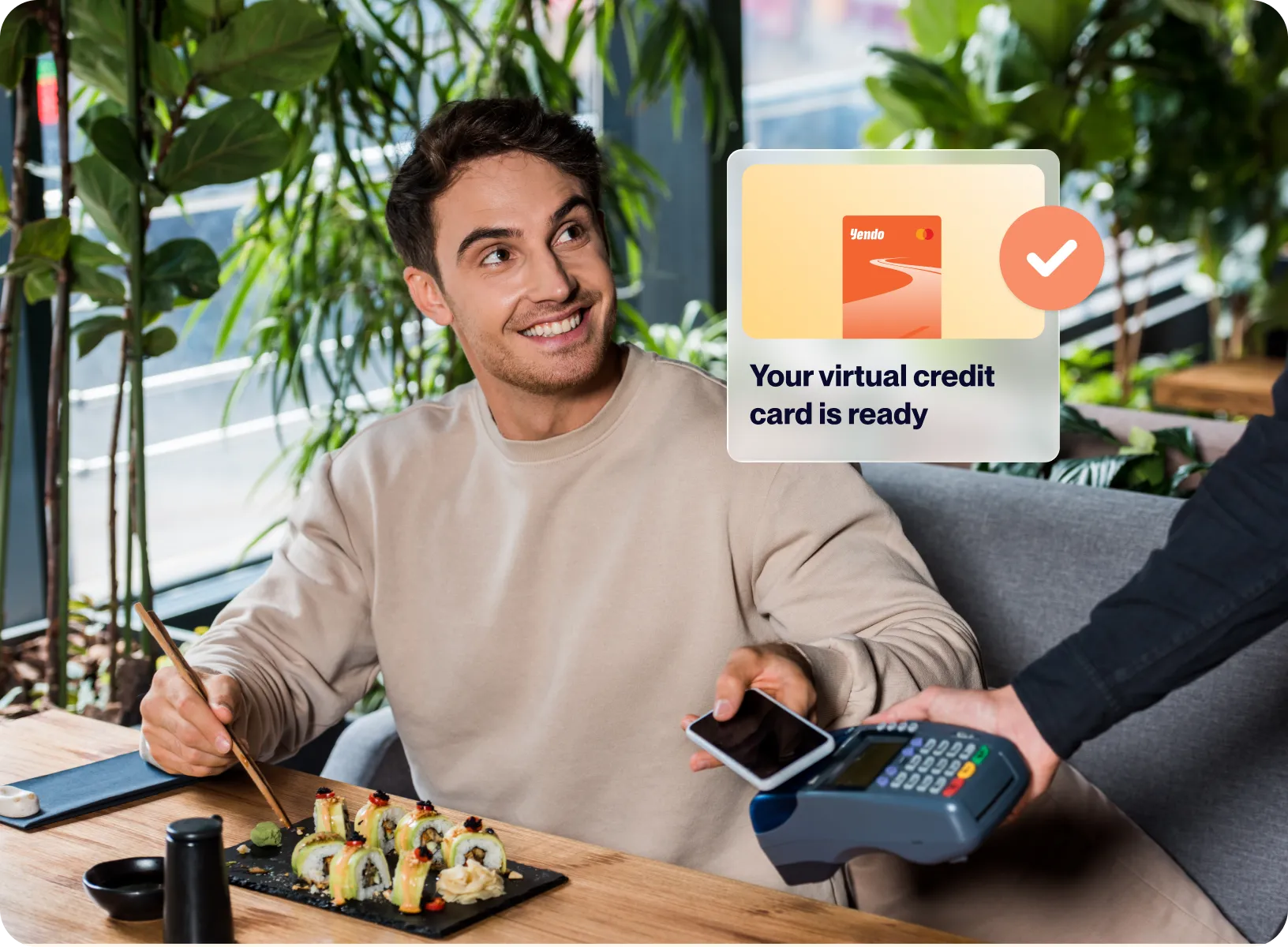 Smiling man about to pay with smartphone using contactless payment at a restaurant with sushi on the table.