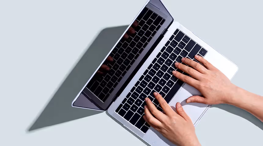 hands resting on the keyboard of an open laptop used to illustrate market research payments