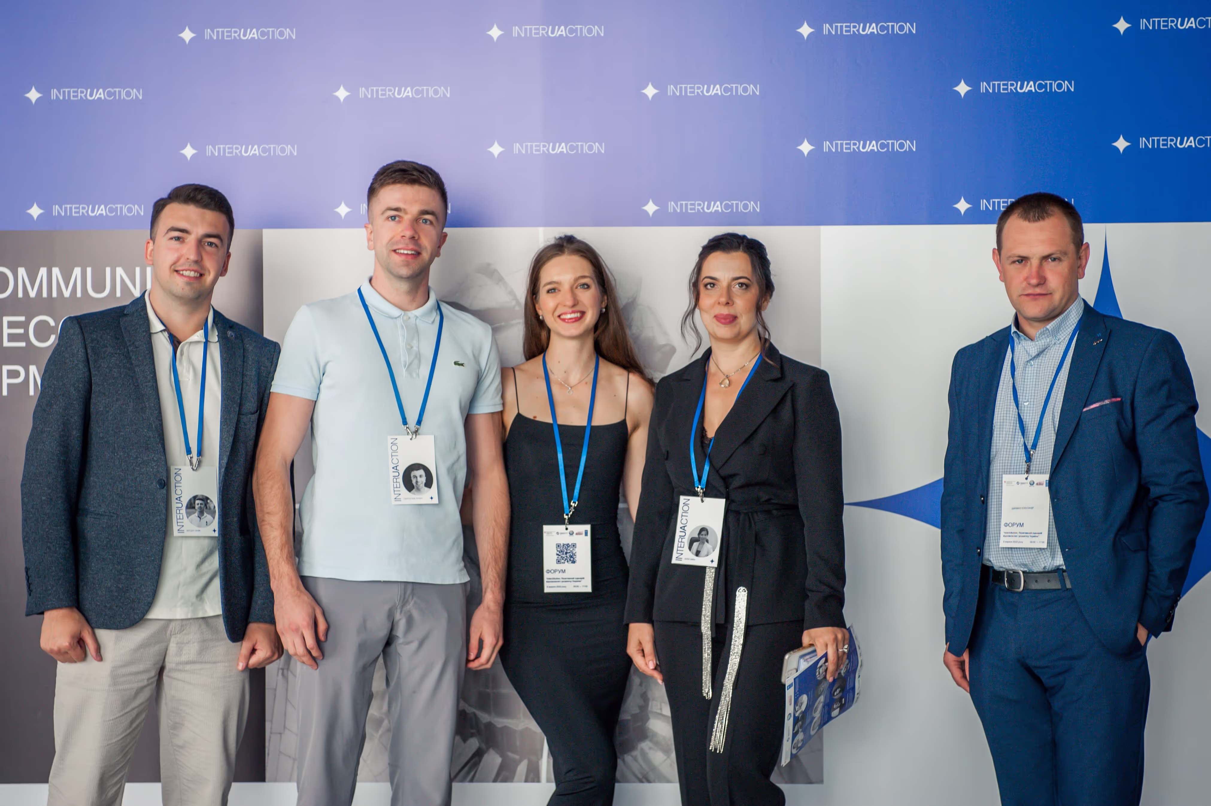 Учасники події з бейджами на тлі пресвола InterUAction