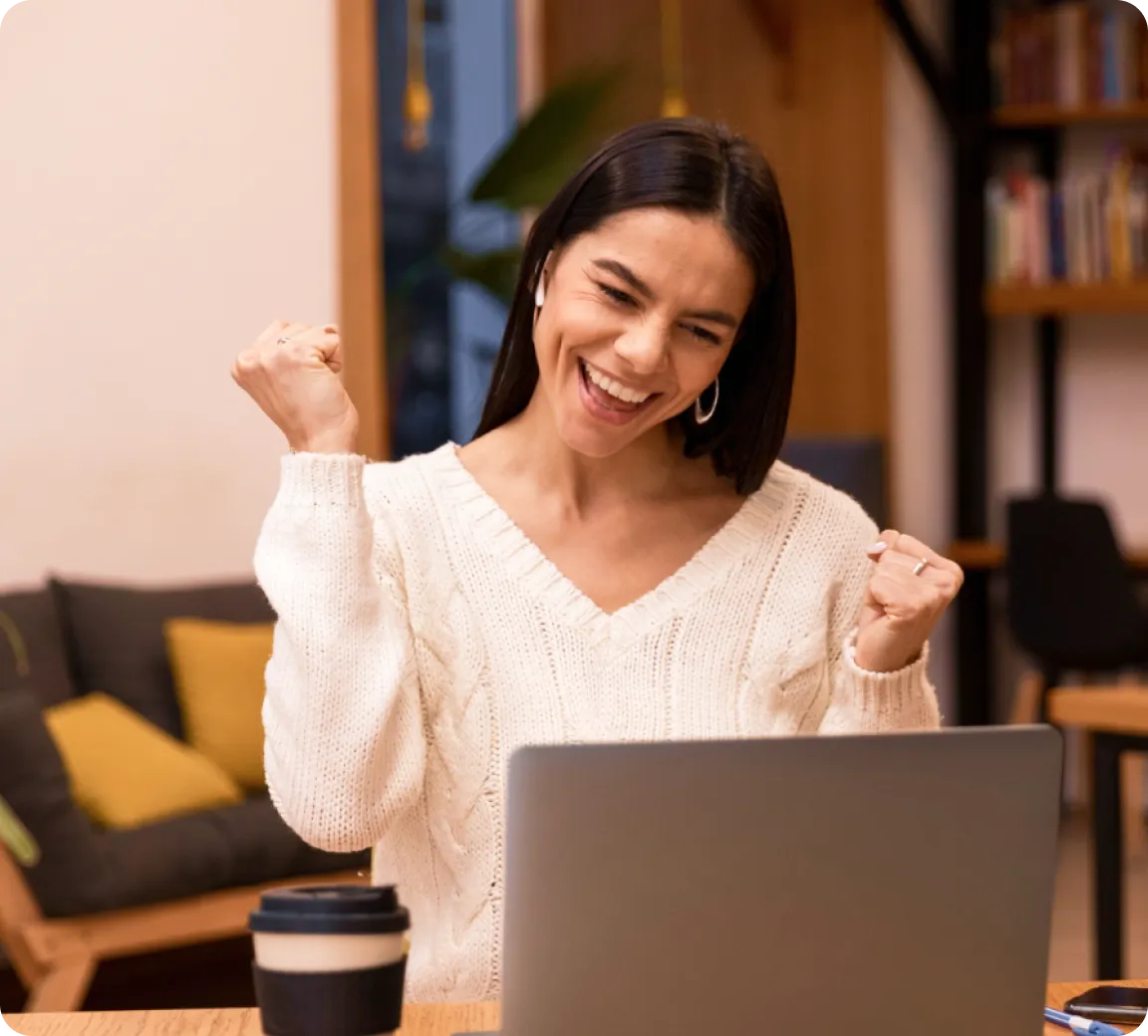 Happy employee celebrating successful enterprise device management setup on laptop in a modern workspace.
