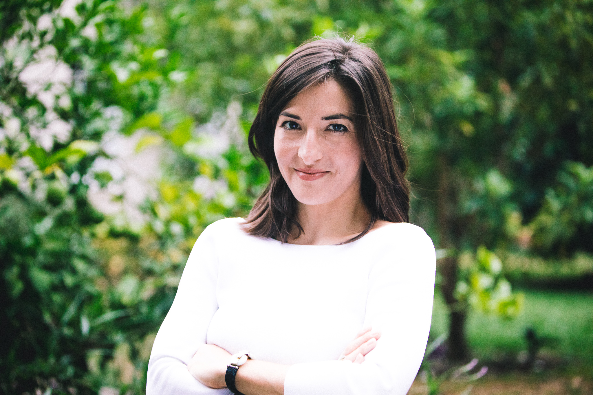 A brunette woman with her arms folded poses for a portrait photo.