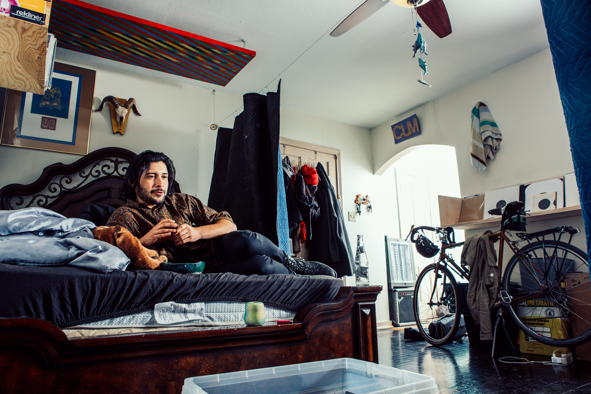 A mam lays on his bed in a rustic and average looking room.