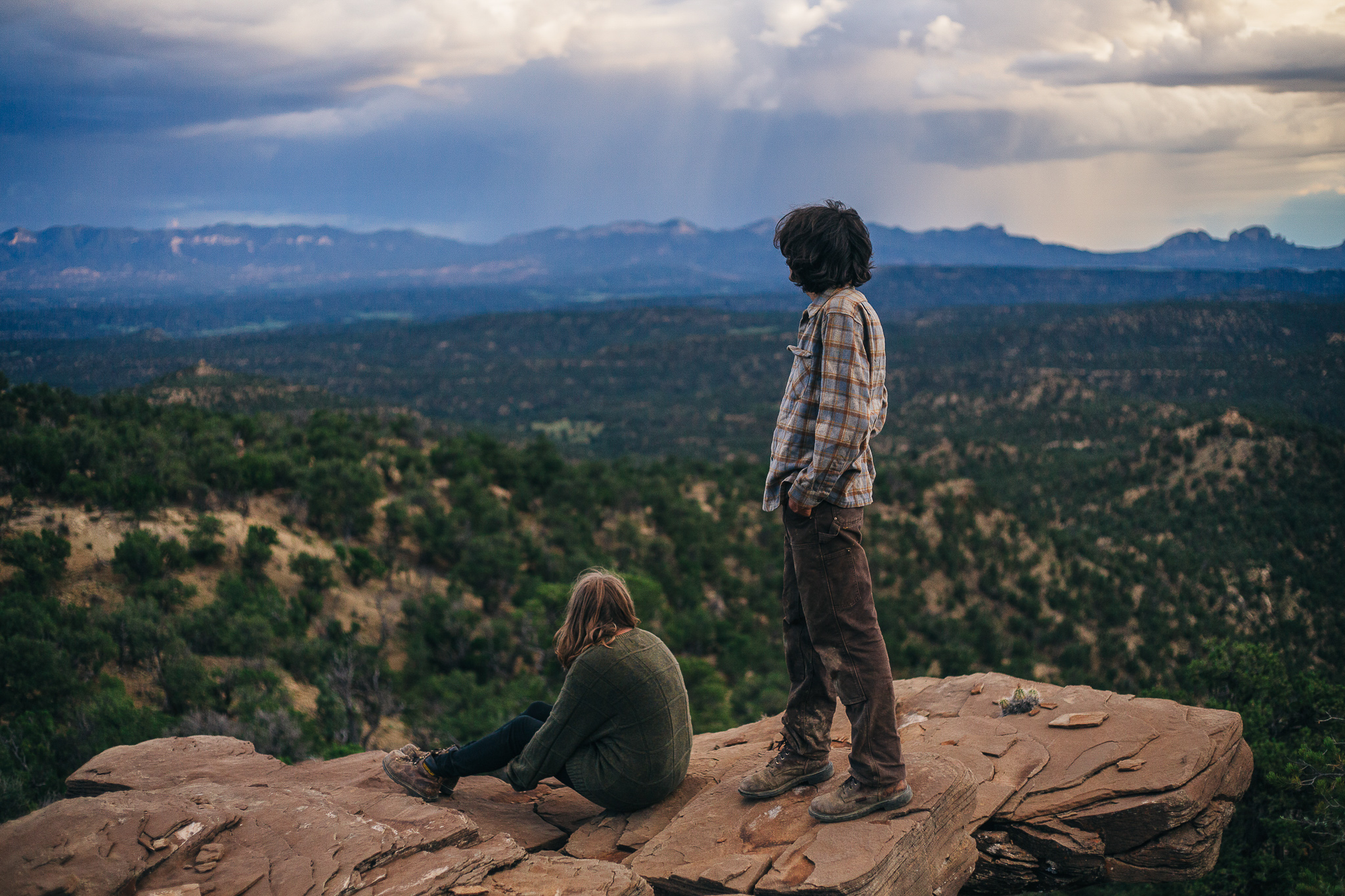 A man and a woman over look a a view from a cliff.