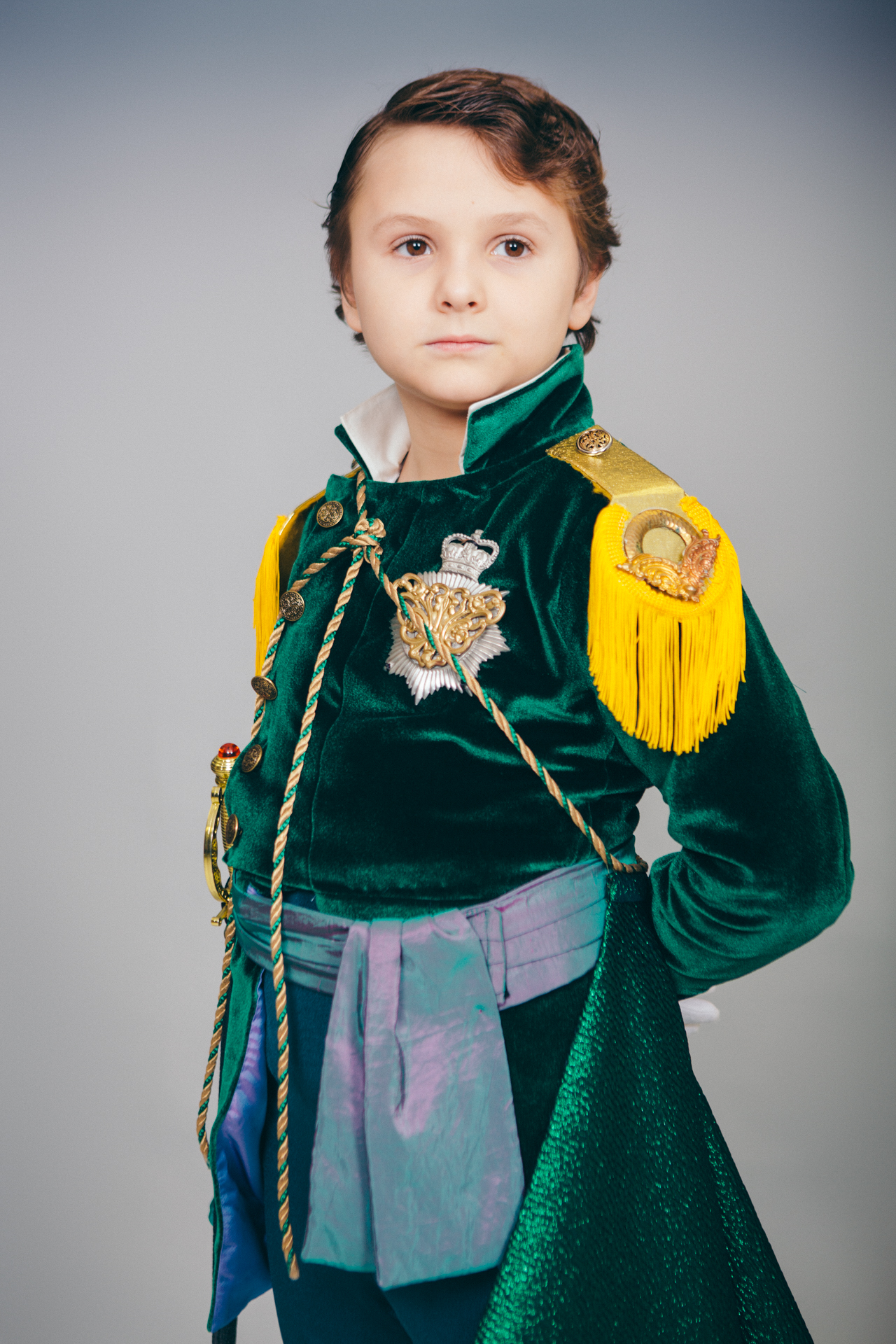 A little boy in a green admirals suit poses for a portrait picture