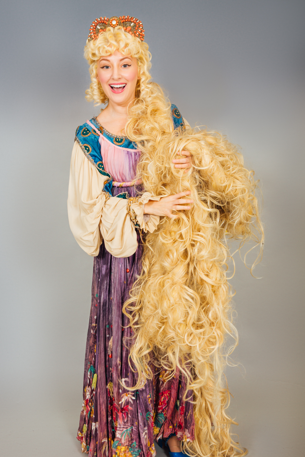 A Rapunzel type character poses for a portrait photo with her long blonde hair