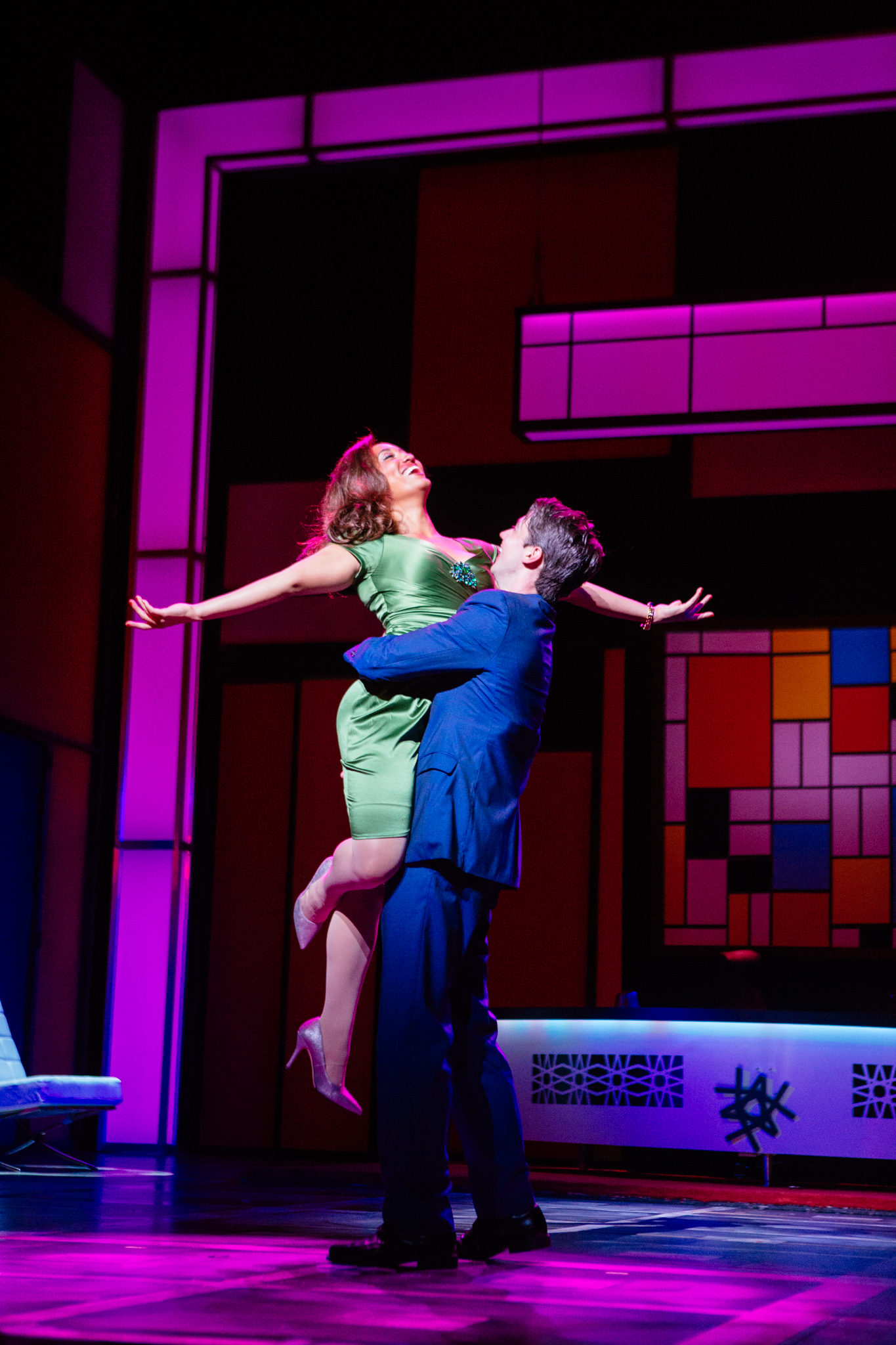 A man holds a woman with her arms out above himself on stage