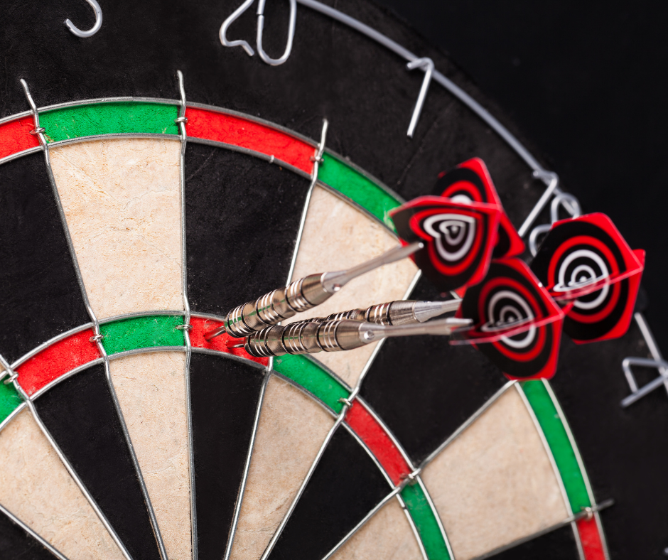Close up of dart board with three darts in the triple twenty