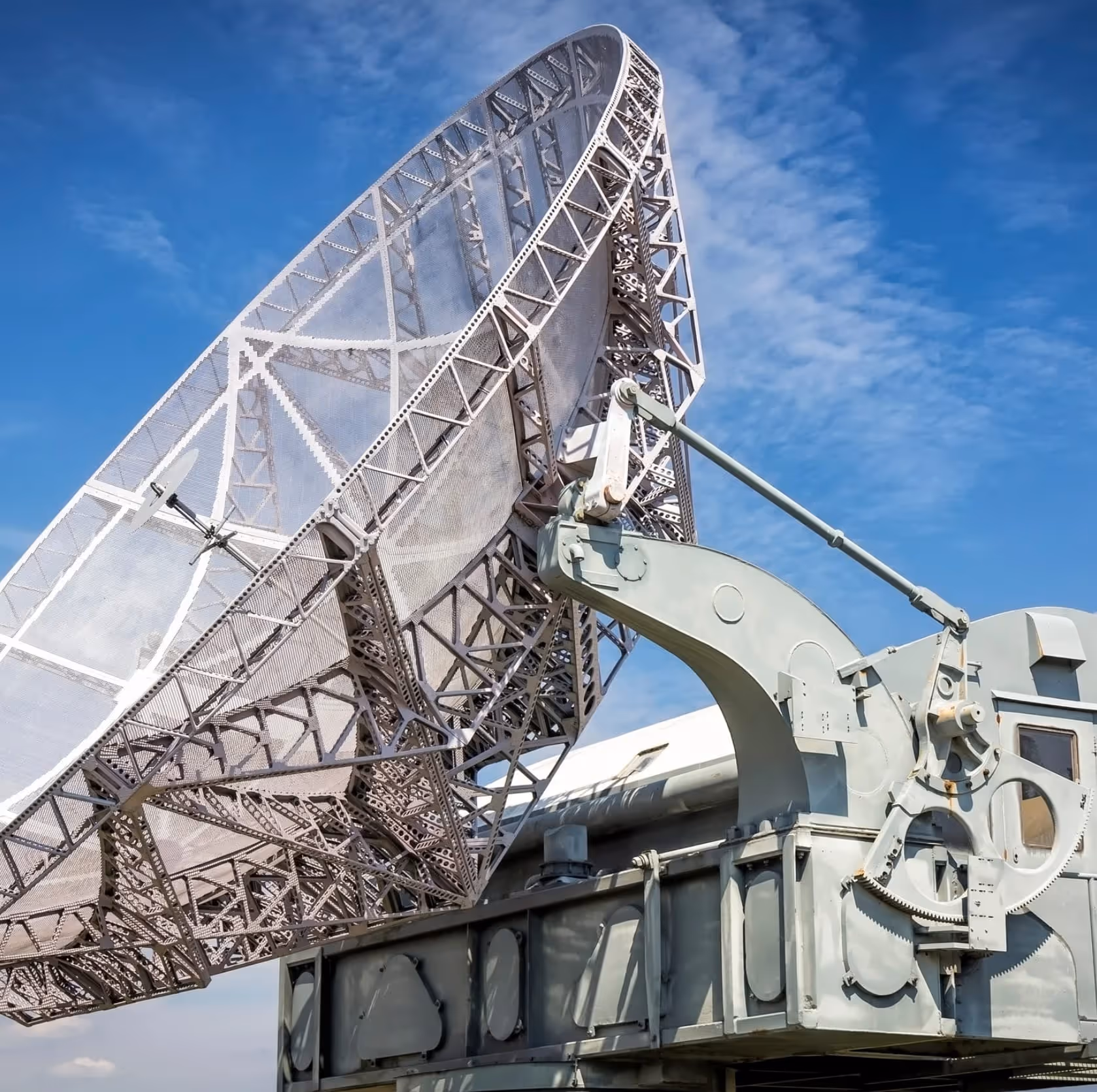 Grande antenne parabolique métallique sous un ciel bleu.