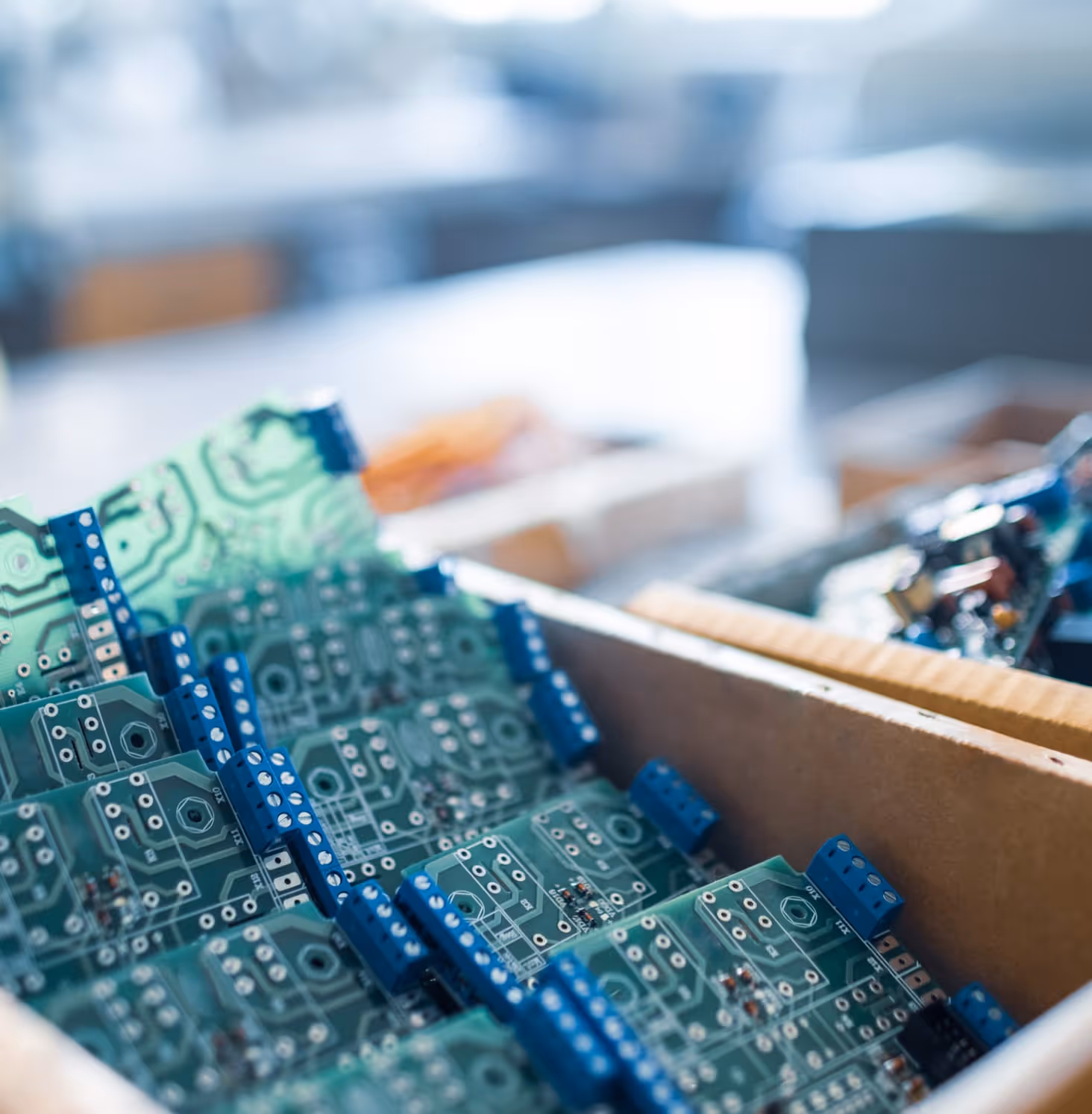 Gros plan sur des circuits imprimés verts empilés avec des connecteurs bleus à l'intérieur d'une boîte en carton.