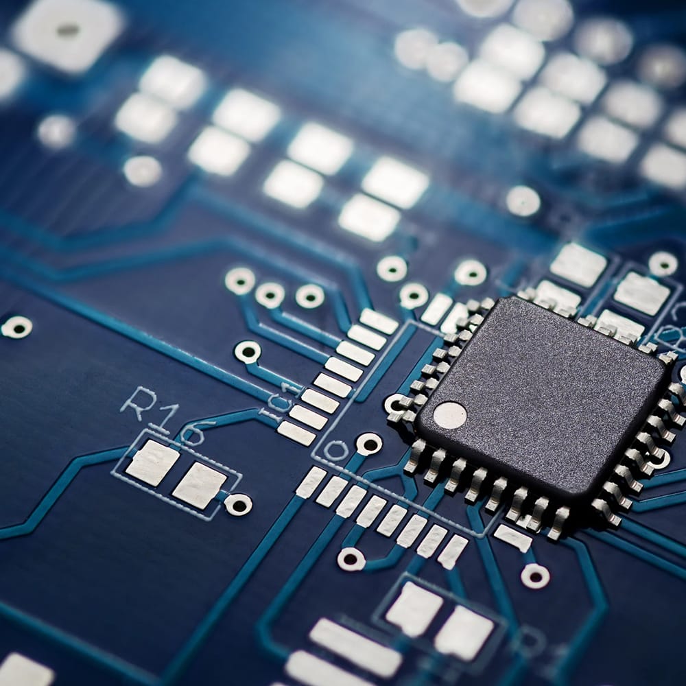 Gros plan d'une micropuce montée sur un circuit imprimé bleu avec traces et points de soudure visibles.