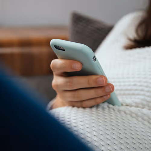 Pregnant mom with phone on belly reading message about getting started with lactation and postpartum support