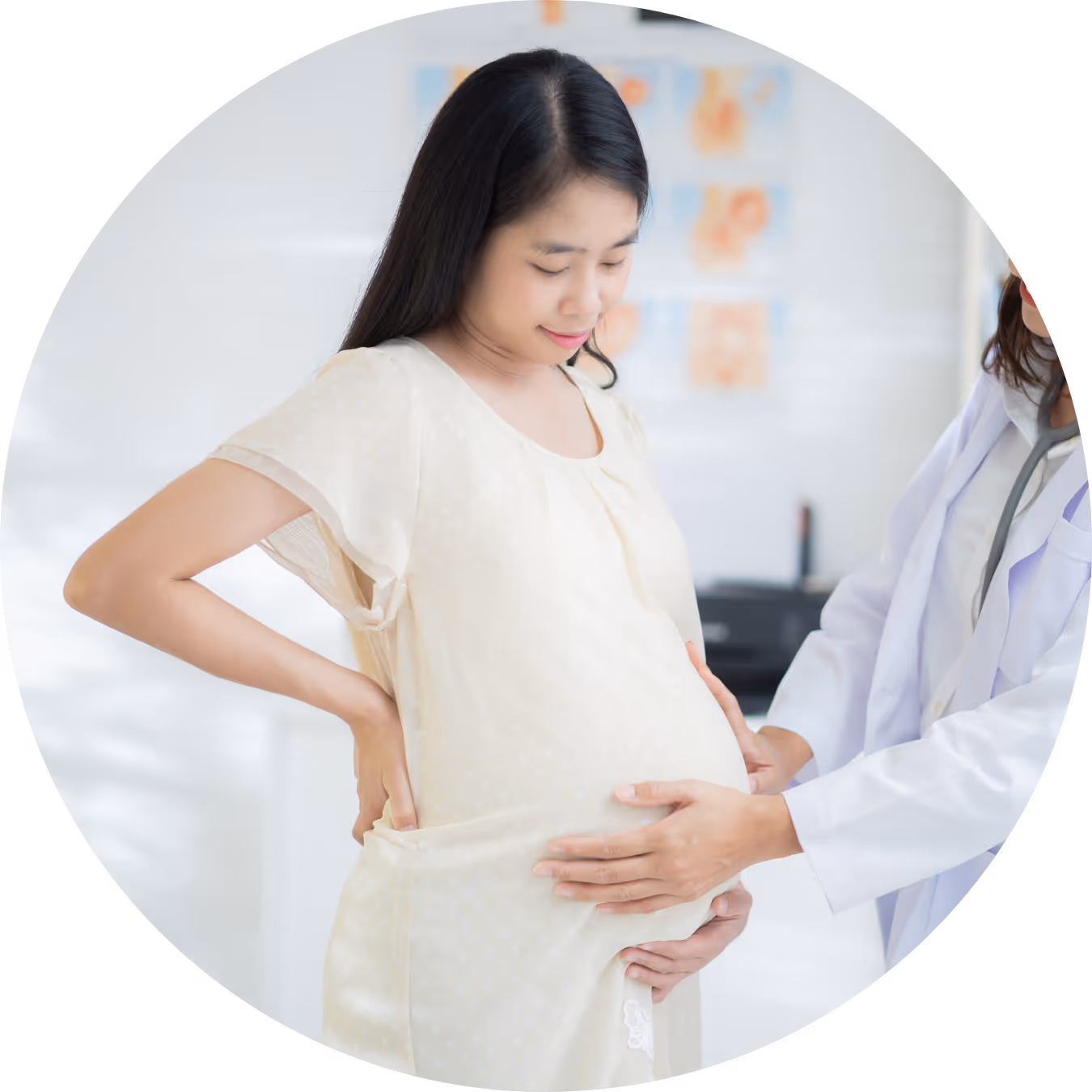 Pregnant woman in a light cream dress having her belly examined by a medical professional in a clinic.