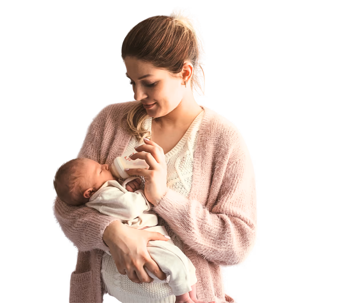 Woman in pink sweater bottle-feeding a baby dressed in white while holding the baby in her arms.