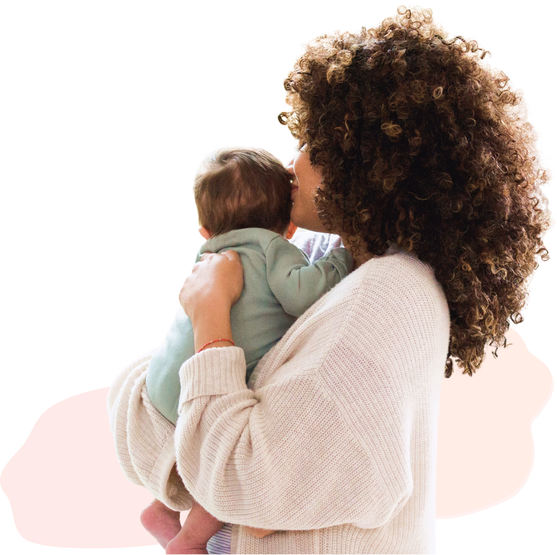 Woman with curly hair holding and kissing a baby wearing a green outfit.