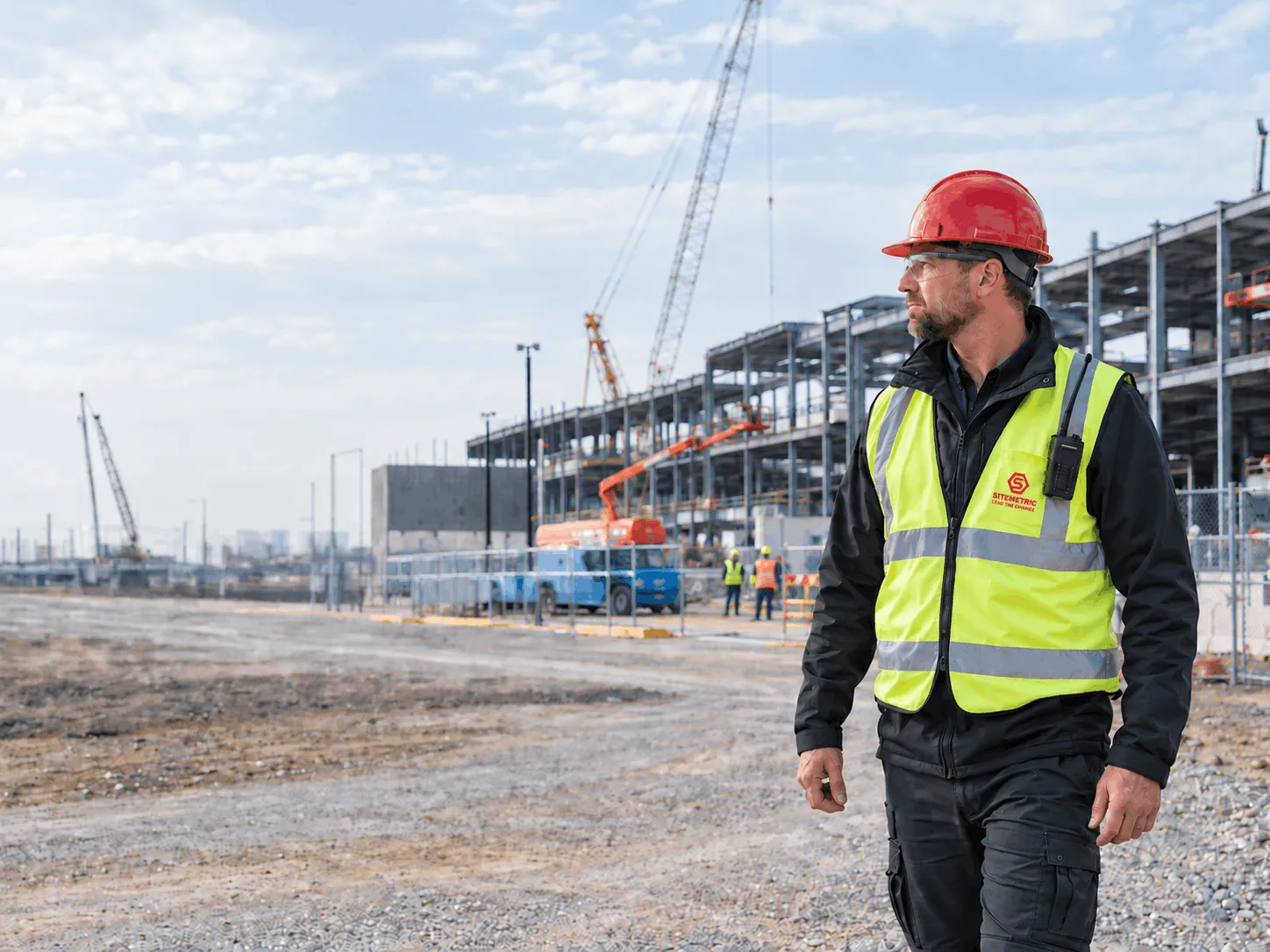A Sitemetric security specialist in a hard hat and high-visibility vest watching an active data center construction site.