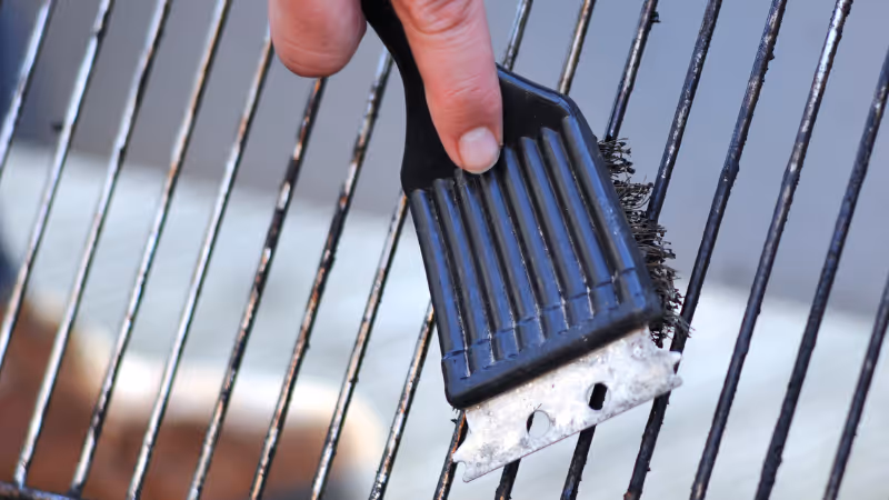 Close up of a grill brush being used to clean