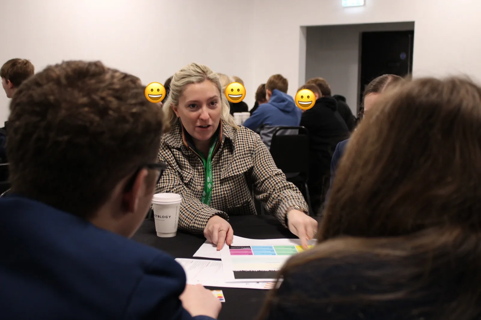 An industry Mentor wearing an Esh Construction lanyard talks through a team workbook with young people at the Innovation Lab, Magna