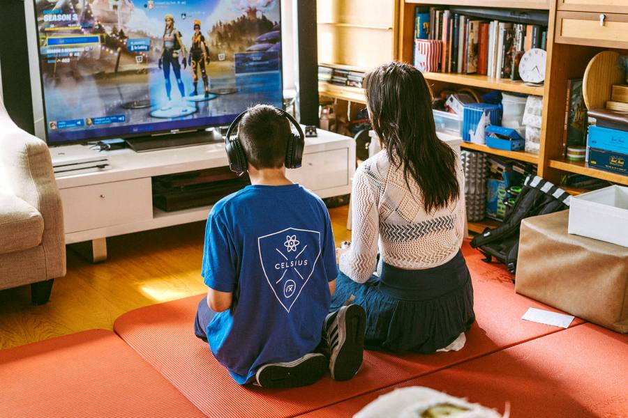 Två personer sitter på golvet framför en tv och spelar tv-spel tillsammans.