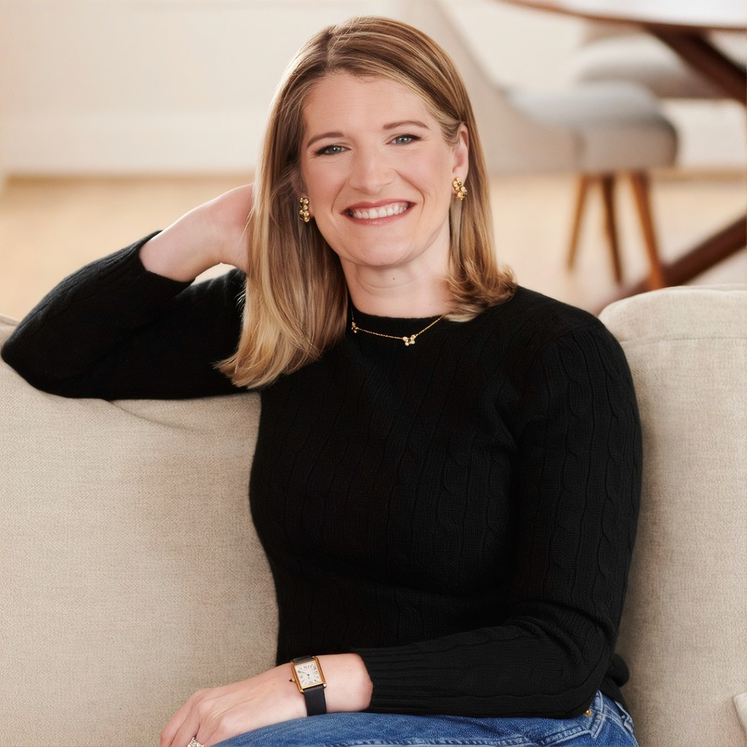 Sam McKenna smiling, seated on a sofa.