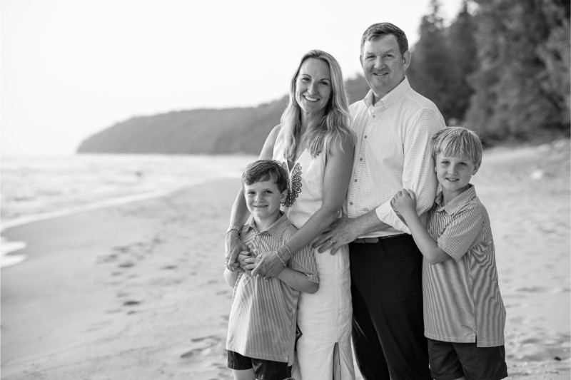 a family of four smiles on the beach