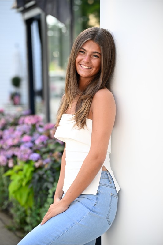 a girl smiles leaning up against a pillar