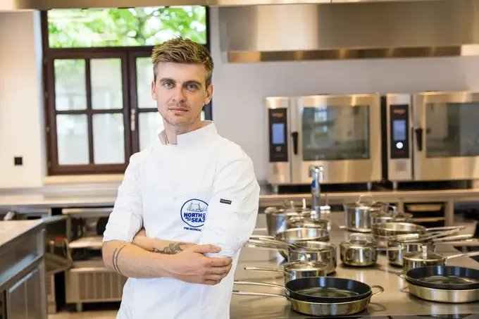 Photo couleur du chef Pim Meiresone en veste de cuisine blanche NorthSeaChefs dans une cuisine professionnelle