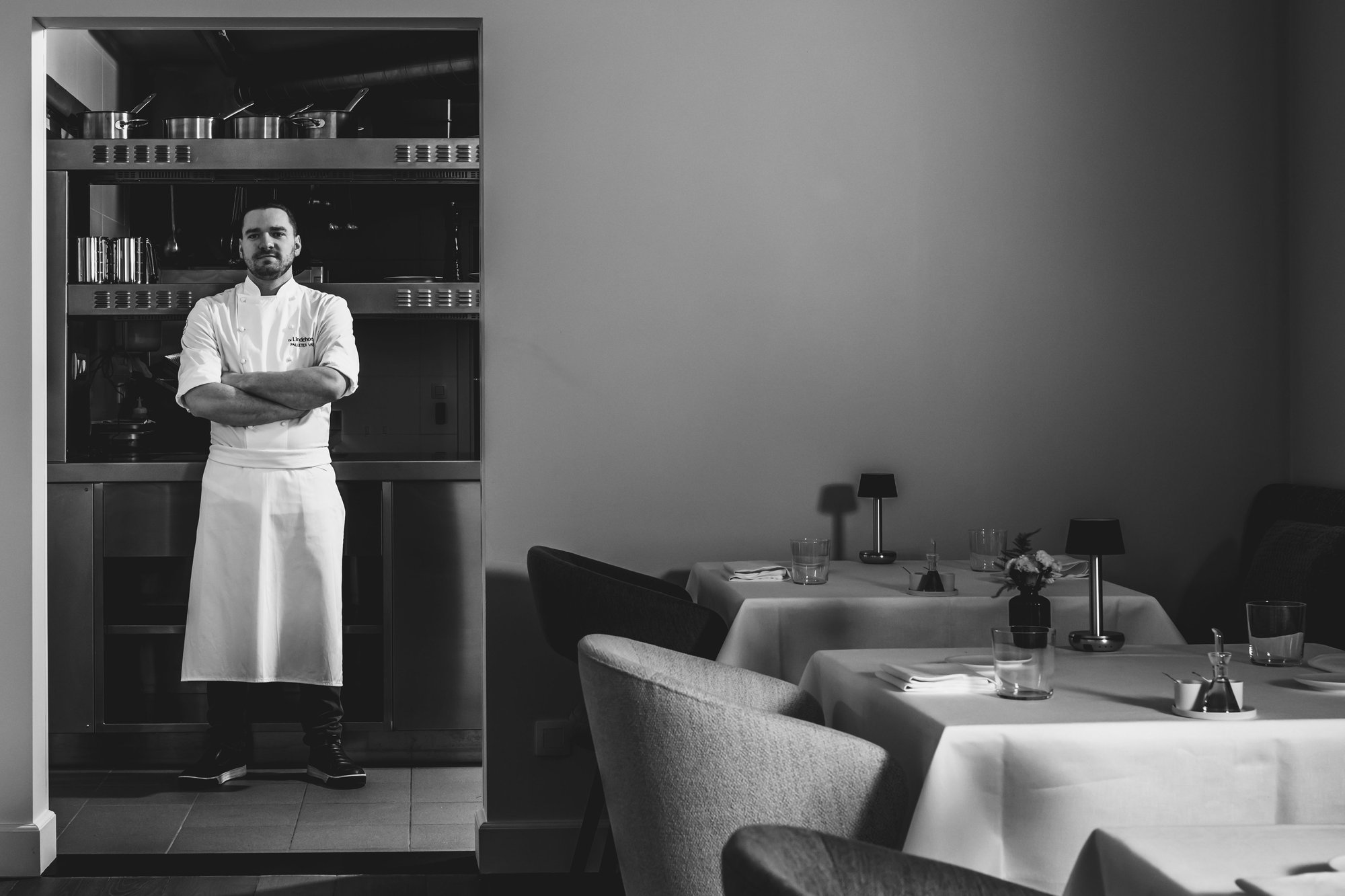 Photo en noir et blanc du chef Pallieter Vaes en veste de cuisine et long tablier au restaurant De Lindehoeve