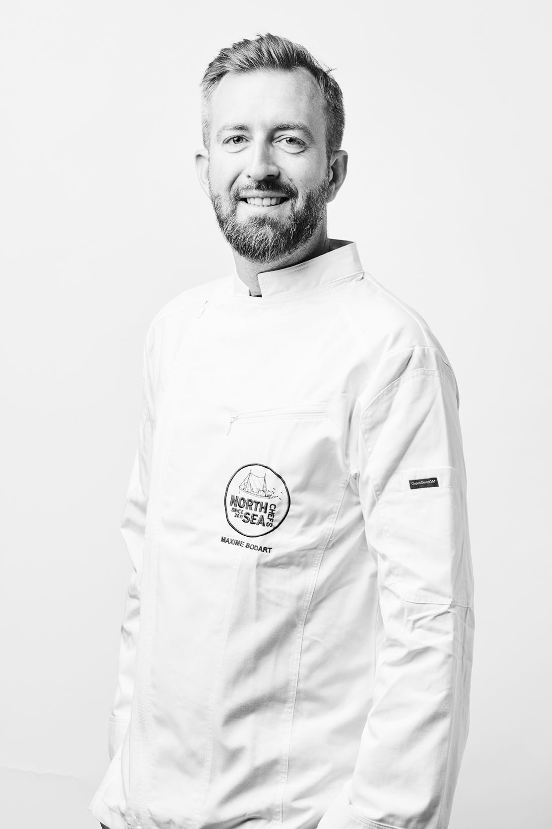 Portrait en noir et blanc du chef Maxime Bodart en veste de cuisine blanche NorthSeaChefs