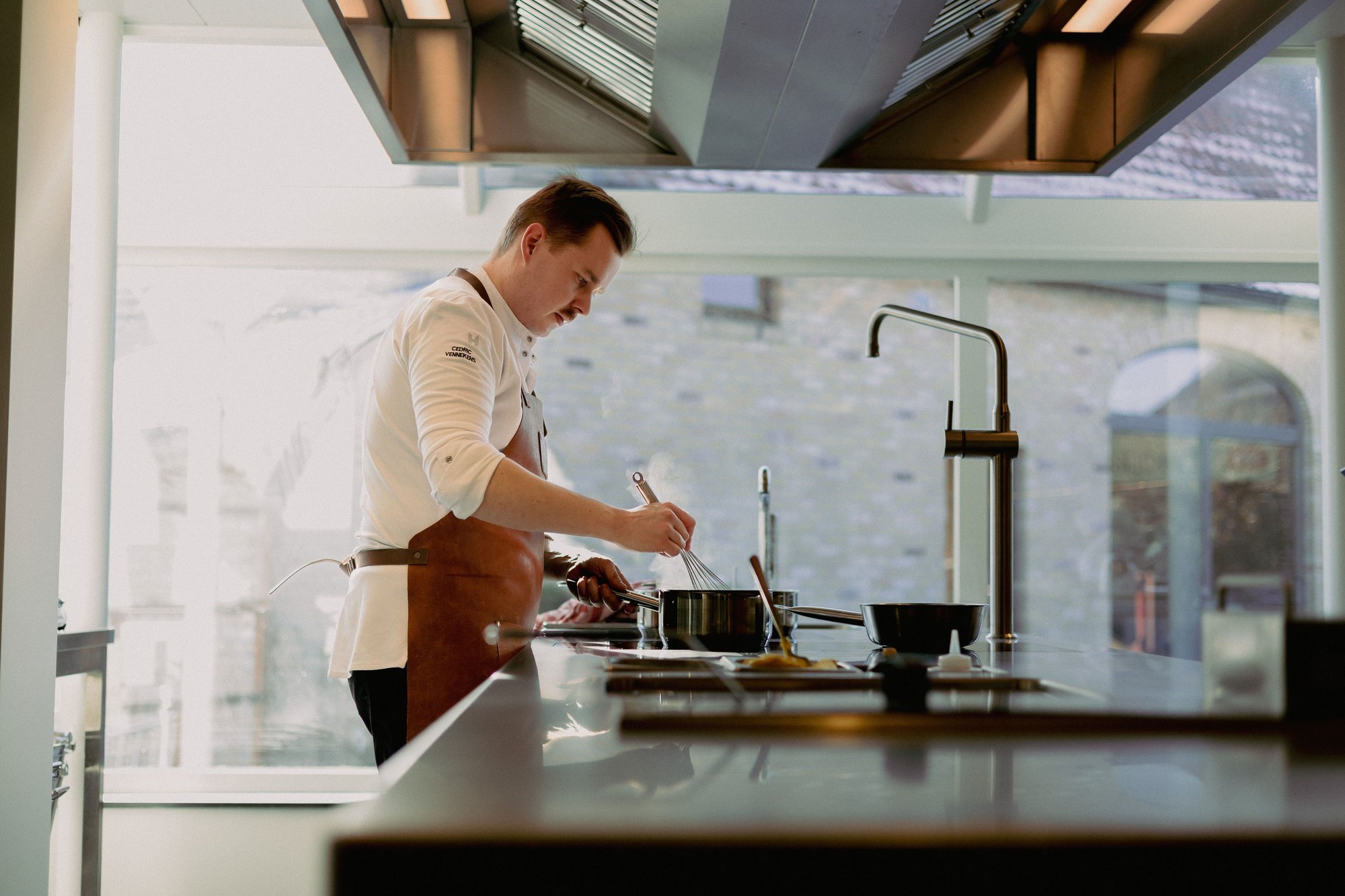 Photo couleur du chef Cédric Vennekens au travail dans la cuisine ouverte du restaurant Marck