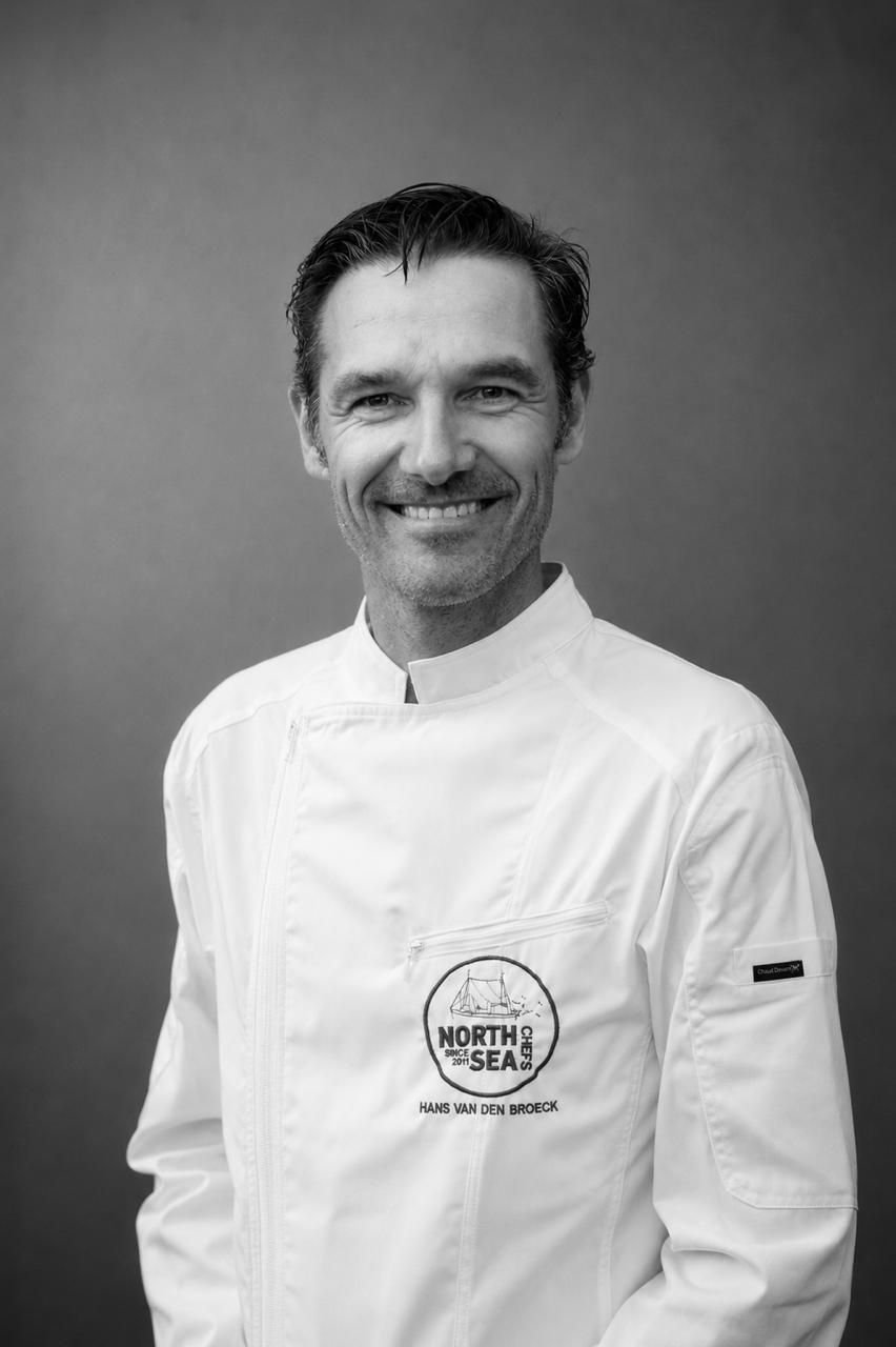 Portrait en noir et blanc du chef Hans Van den Broeck en veste de cuisine blanche NorthSeaChefs
