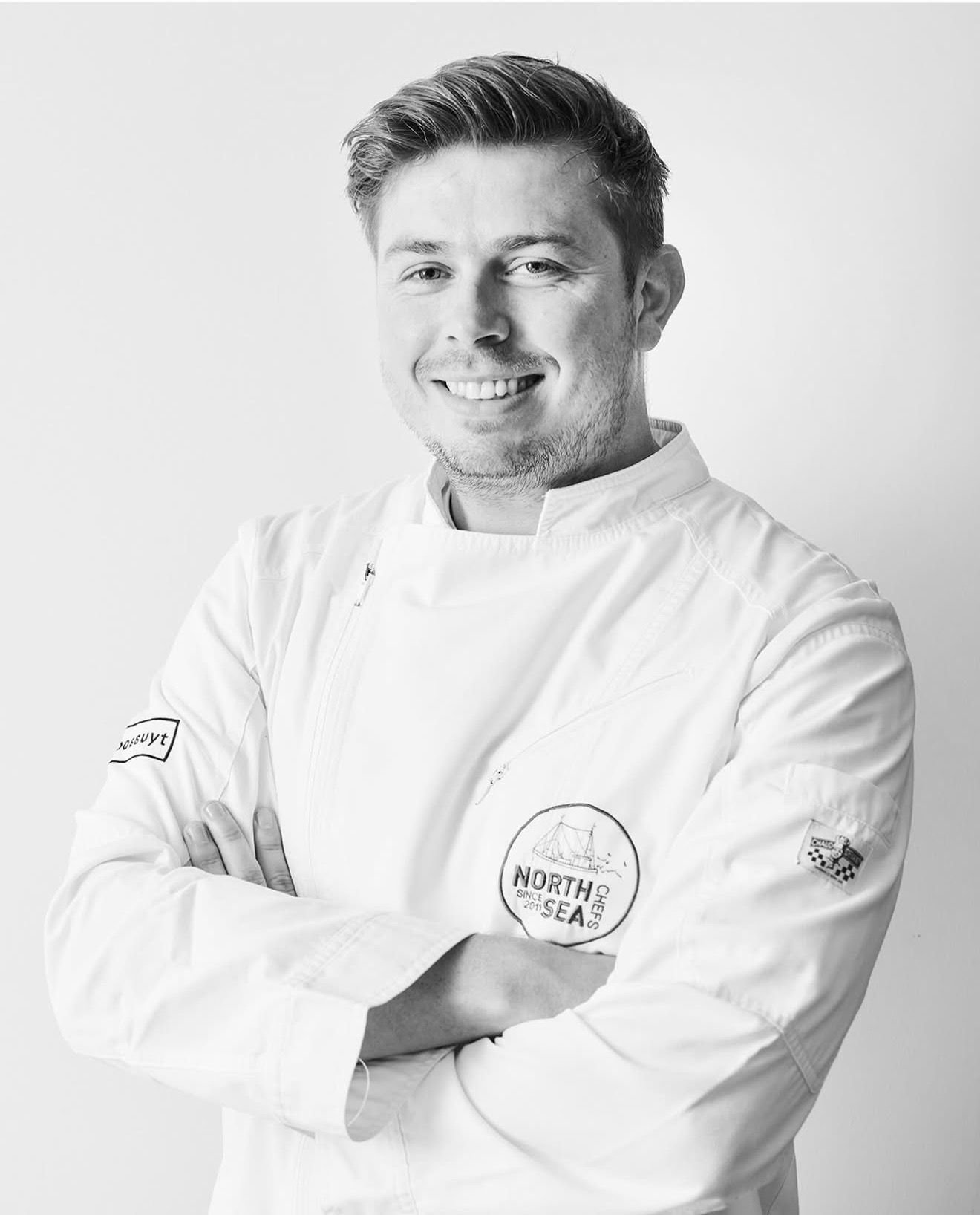 Portrait en noir et blanc du chef Glenn Vanden Broucke en veste de cuisine blanche NorthSeaChefs